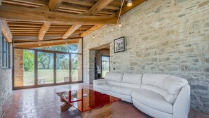Una habitación amplia con sofá de cuero blanco, una mesa de centro de madera y una pared de piedra.