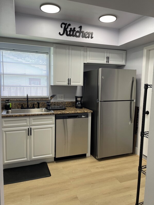 A modern kitchen with white cabinets, a stainless steel refrigerator, and a coffee maker on the counter. - Charming 2-bedroom house in delightful Orlando. Centrally located. (Orlando)