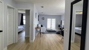 Una habitación amplia con suelo de madera, un espejo grande y una cama.