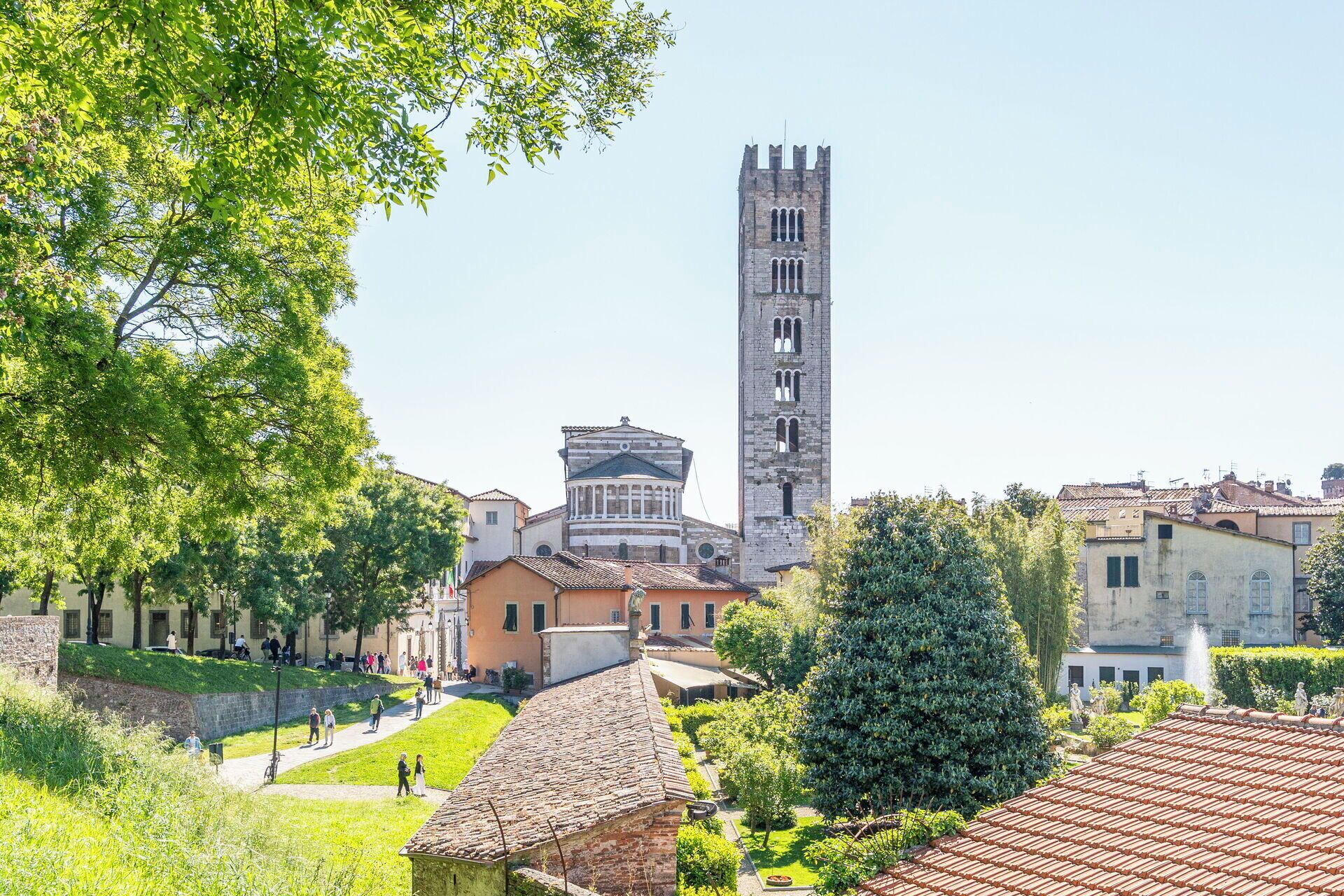 A historic town square with a prominent church tower, a classical building with a dome, and surrounding greenery.