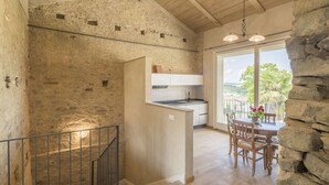 Eine rustikale Küche mit Steinwand, einer Holztreppe und einem Balkon mit Aussicht.