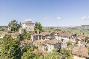 A historic village with stone buildings, a prominent tower, and terraced fields in the background. - Arpusè - Ca Fredo Apartment With Pool (Monforte D'alba)