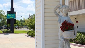 A statue of a woman holding flowers in front of a building with a sign for Carom Inn. - Carom Inn Denham Springs-Baton Rouge (Denham Springs)