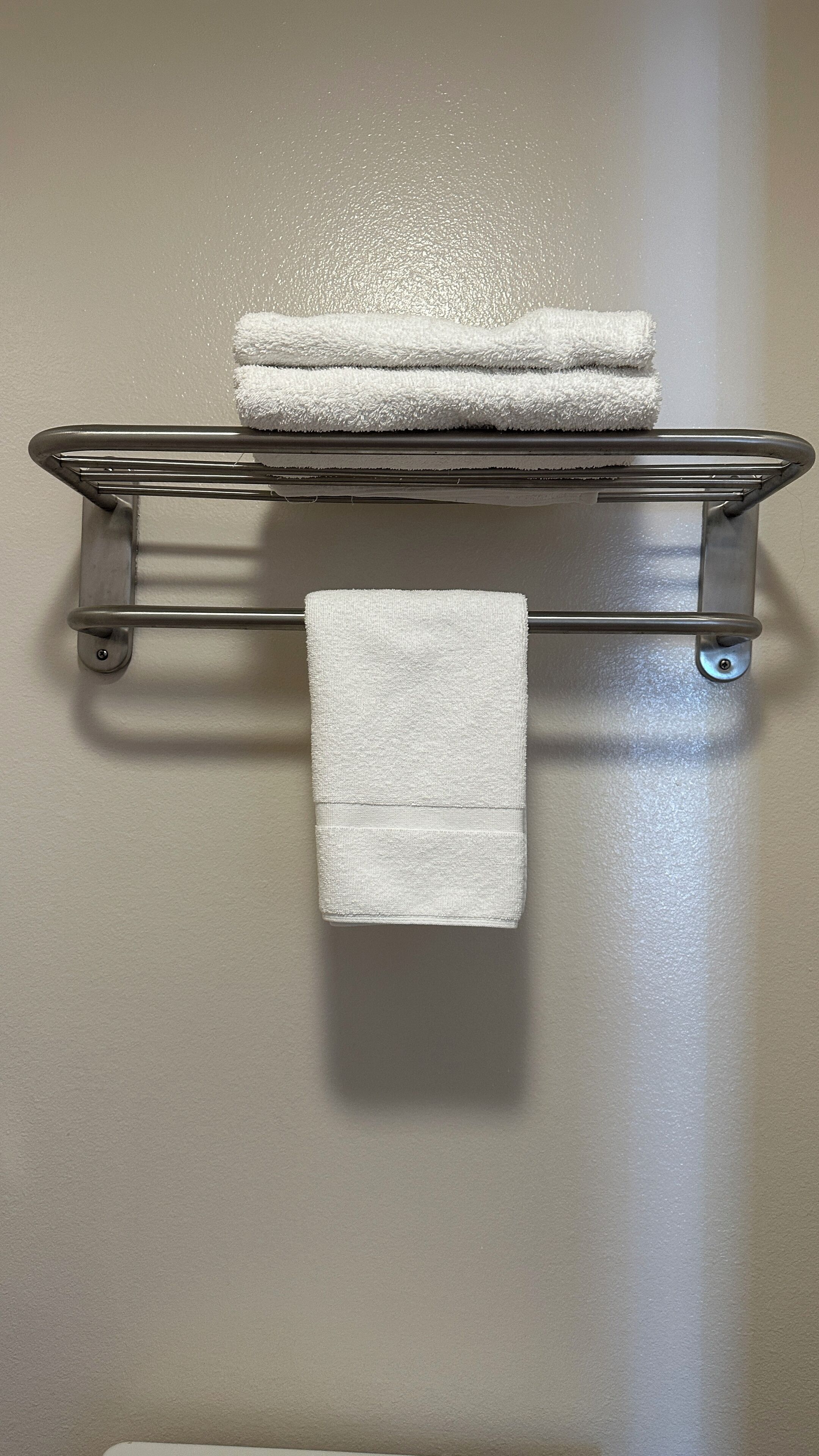 A metal towel rack with two folded white towels.