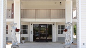 A building with a double door entrance, numbered 2311, flanked by two statues holding flowers. - Carom Inn Denham Springs-Baton Rouge (Denham Springs)