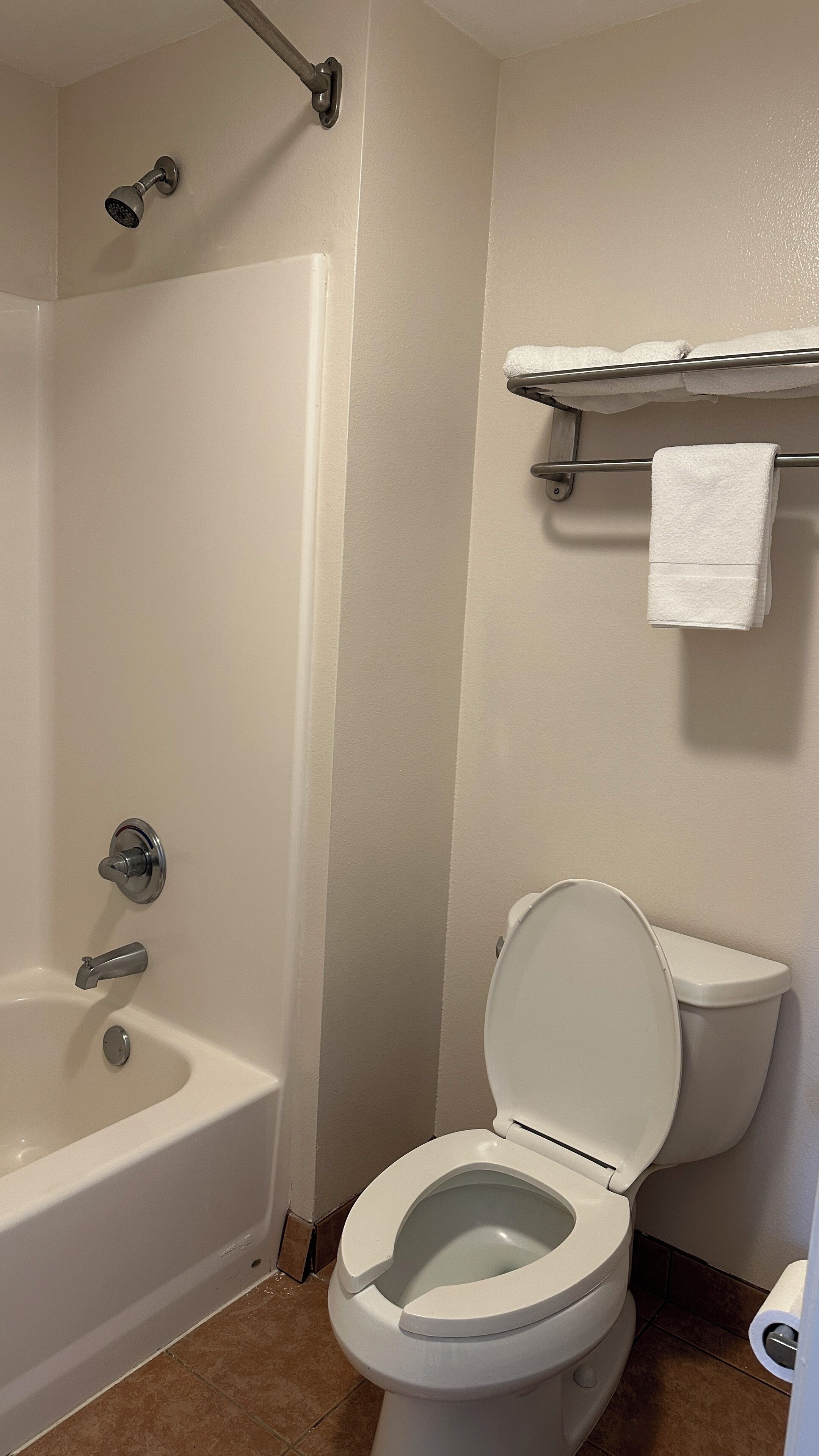 A bathroom with a bathtub, toilet, and a towel rack.