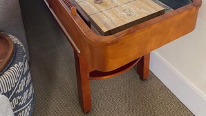 A shuffleboard table with pucks, a mirror, and a carpeted floor.