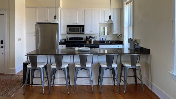A modern kitchen with white cabinets, stainless steel appliances, and a central island with bar stools.