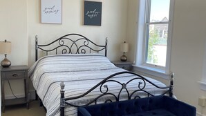A bedroom with a bed, a nightstand, a bedside lamp, a ceiling fan, and a window.