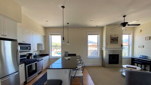 A modern kitchen with stainless steel appliances, a central island, and a fireplace.