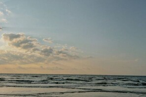 A beach with waves and a partly cloudy sky.