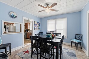 Uma área de refeições com ventilador de teto, um relógio e vista para a cozinha.