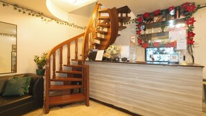 Eine Hotelhalle mit einer Holztreppe, einem Empfangstresen und einer Wand, die mit Weihnachtssternen geschmückt ist.