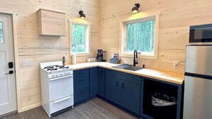 Une cuisine moderne avec des murs en bois, une cuisinière, des placards, un évier et un réfrigérateur.