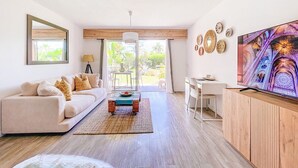 Ein modernes Wohnzimmer mit Sofa, Couchtisch, Fernseher und Essbereich.