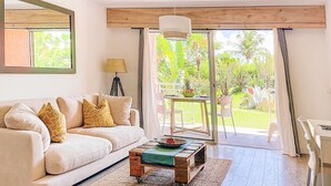 Ein Wohnzimmer mit einer Couch, einem Couchtisch und einem Balkon mit Tisch und Stühlen.