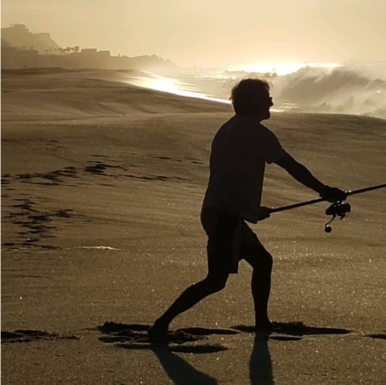 A person walking on a beach with waves in the background.