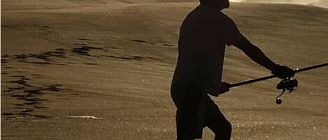 A person walking on a beach with waves in the background.