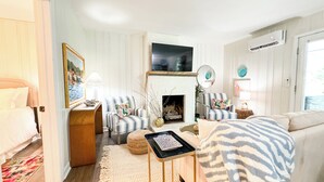 Una sala de estar acogedora con chimenea, sillones a rayas, un sofá y un televisor.