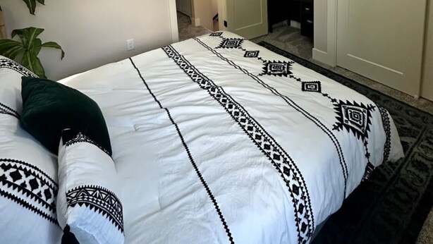 Ein Schlafzimmer mit Bett, einer Tür, einer Wanddekoration und einer Deckenleuchte.