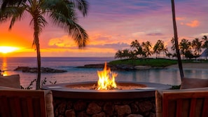 Un fuoco con vista sull'oceano e palme al tramonto.