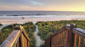 A wooden boardwalk leading to a beach with the ocean in the background. - Southern Charm of Holden Beach (Supply)