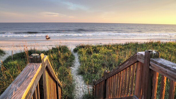 A wooden boardwalk leading to a beach with the ocean in the background. - Southern Charm of Holden Beach (Supply)
