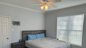 Un dormitorio con cama, mesita de noche y ventilador de techo.