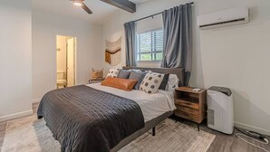 Une chambre à coucher avec un lit, une table de chevet, un radiateur et une fenêtre avec des rideaux.