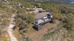 Vue aérienne d’une propriété dotée d’une grande terrasse, d’un espace clôturé et d’un chemin de terre menant à une maison.