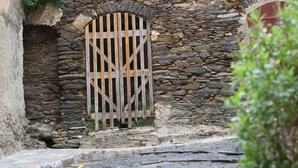 Ein Steinhaus mit einem hölzernen Tor und Stufen, die zu ihm hinaufführen.