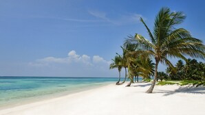A beach with white sand and clear turquoise water. - New Lake Front Villa in Golf and Beach Resort (Punta Cana)