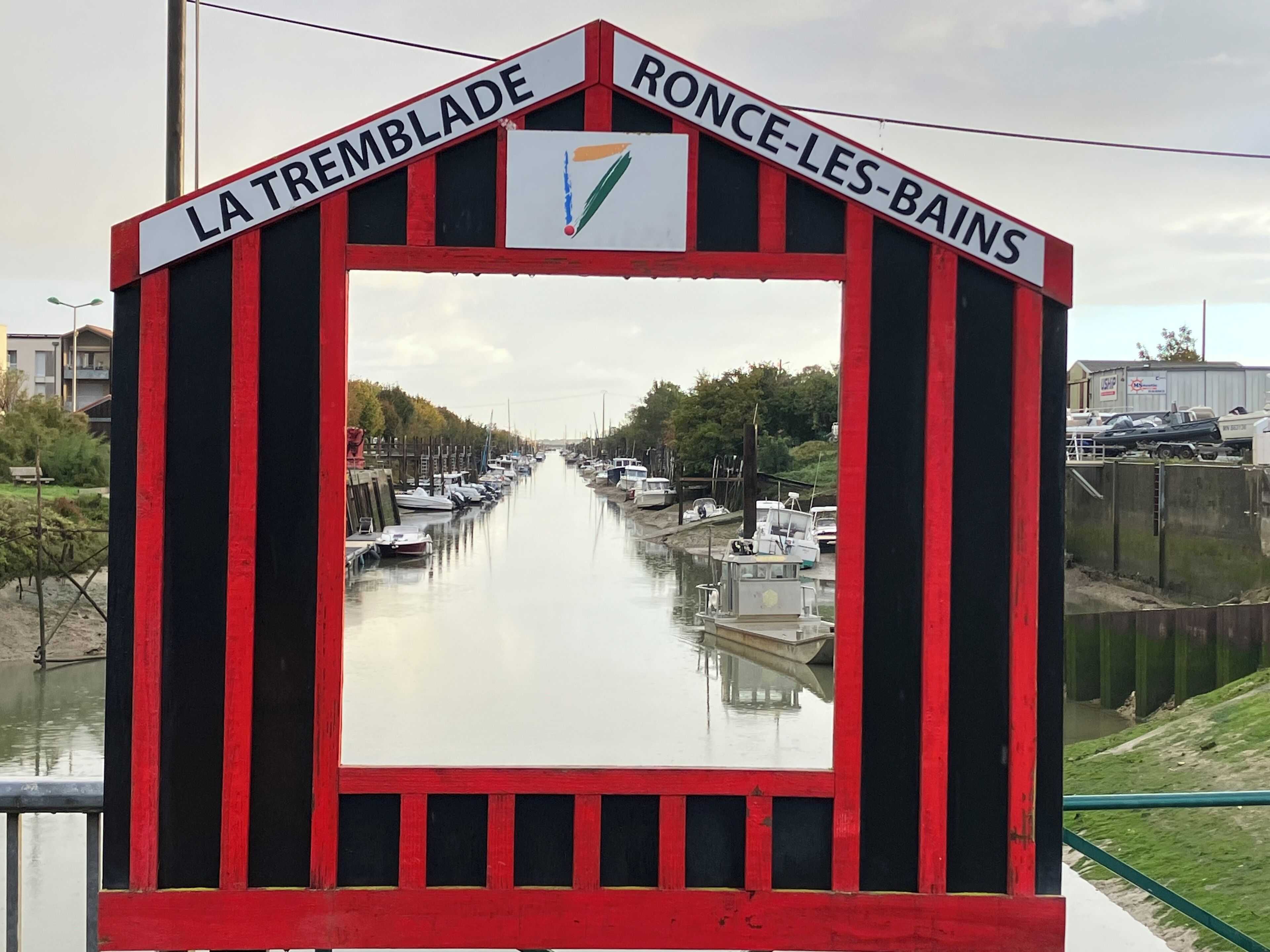 Um canal com barcos, rodeado por vegetação e edifícios.