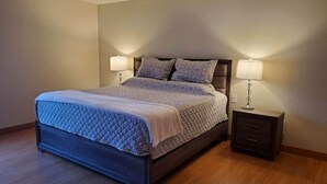 Un dormitorio con una cama, dos mesitas de noche y una mesita auxiliar.