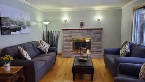 Una sala de estar con dos sofás, una mesa de centro, una chimenea y un cuadro en la pared.