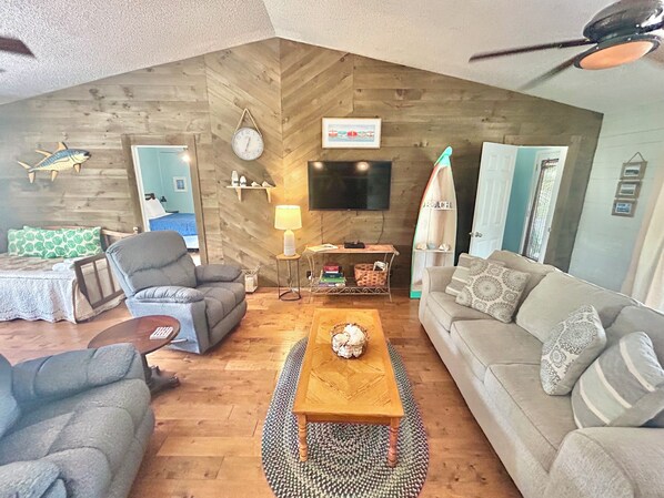 A cozy living room with a wooden ceiling, a sofa, a coffee table, and a television. - Our Anchor - close to the beach! (St. George Island)