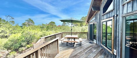 A wooden deck with a table and chairs, overlooking a forested area.