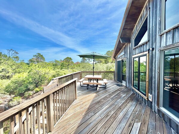 A wooden deck with a table and chairs, overlooking a forested area.