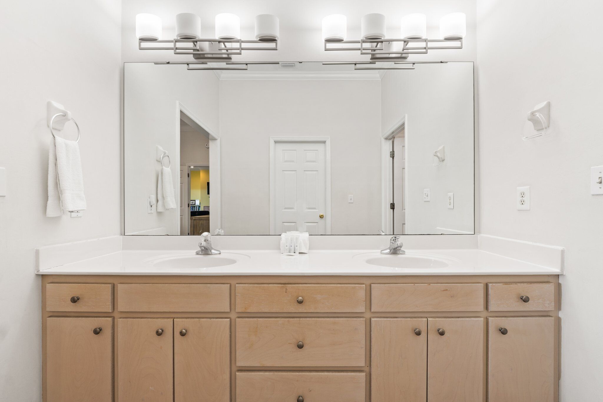 A bathroom with two sinks, a large mirror, and a wooden vanity with drawers.