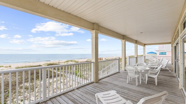 A covered deck with white chairs and tables, overlooking a beach with a clear sky. - See Escape-Beachfront, Pet Friendly, Hot Tub 4BR (St. George Island)