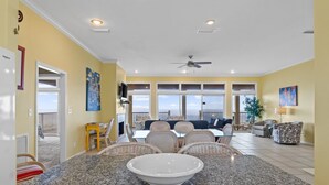 A spacious living area with a large dining table, comfortable seating, and a view of the outdoors. - See Escape-Beachfront, Pet Friendly, Hot Tub 4BR (St. George Island)