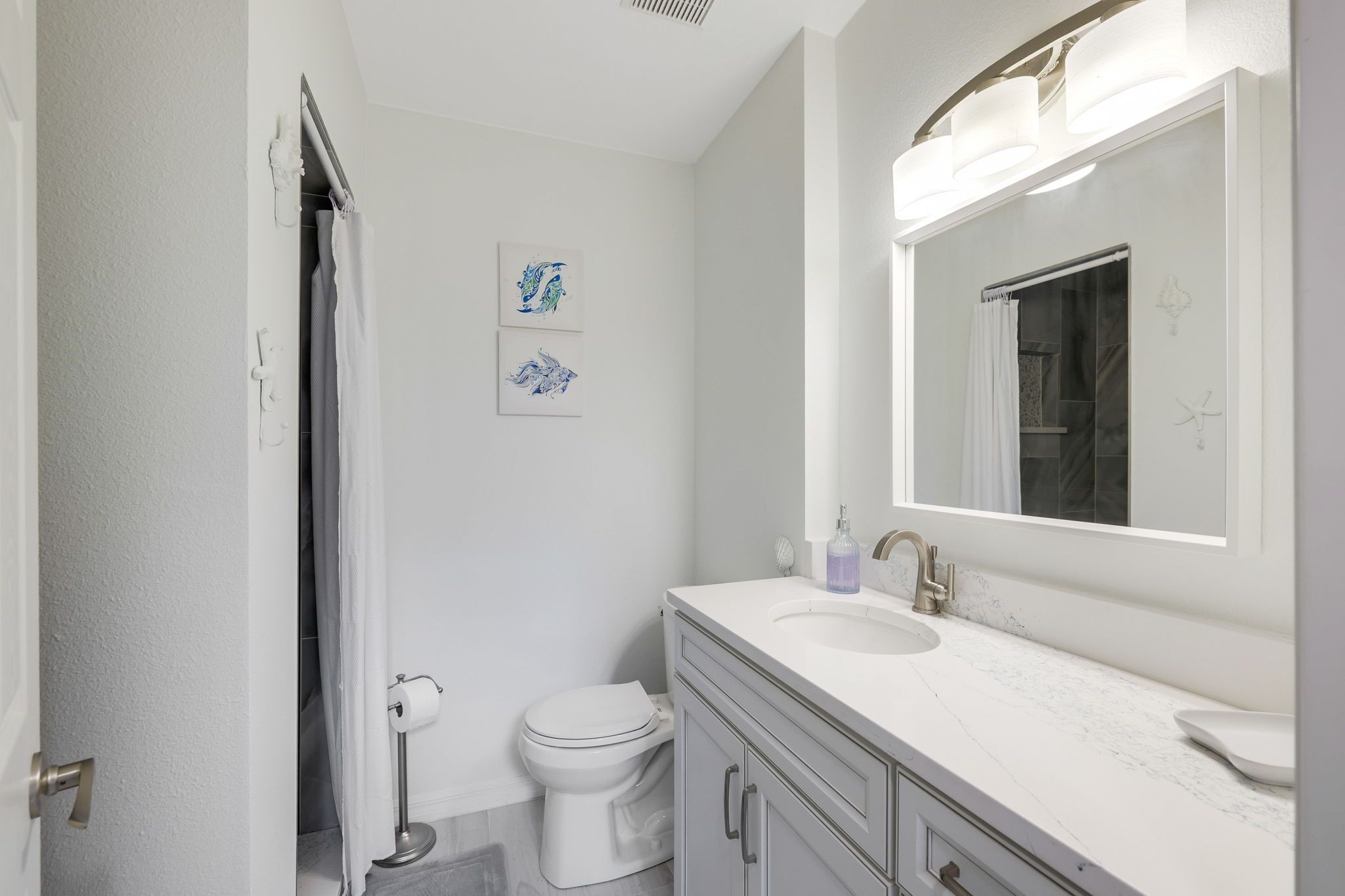Een badkamer met een wit toilet, een wastafel met spiegel en een douchegordijn.