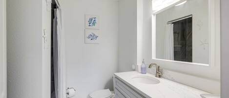 Een badkamer met een wit toilet, een wastafel met spiegel en een douchegordijn.