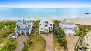 A coastal property with a large house, a smaller building, and a beach view.