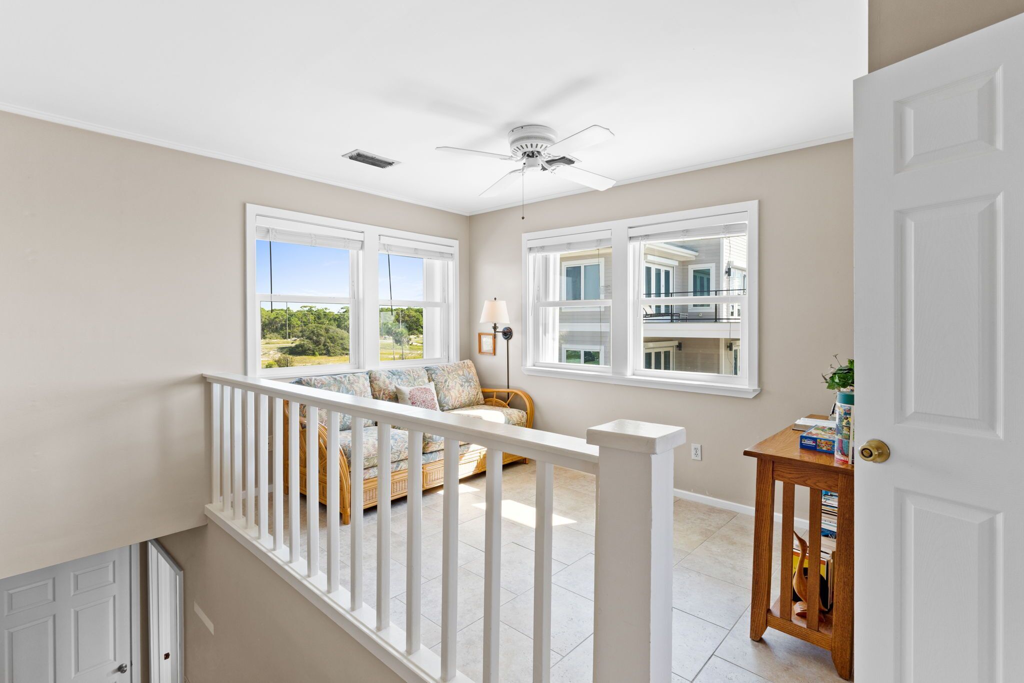 Una habitación amplia con ventanas grandes, ventilador de techo y vistas al exterior.