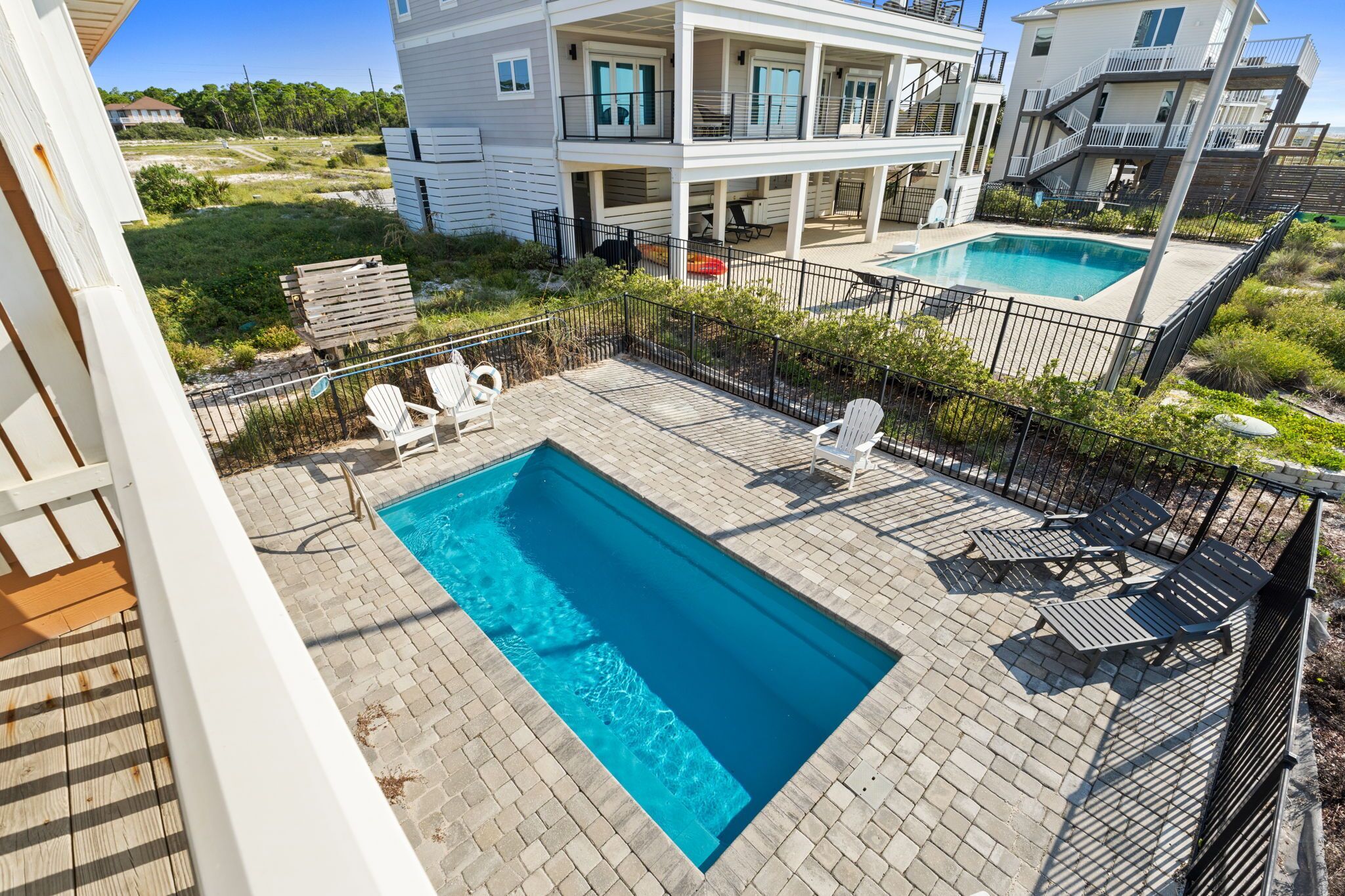 A residential property with a swimming pool, outdoor seating, and a view of neighboring houses.