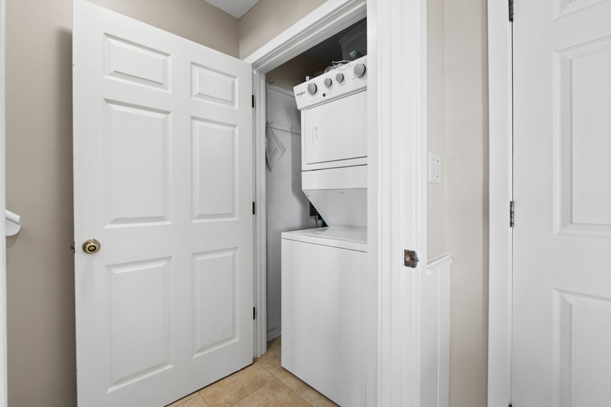 A laundry room with a washer and dryer, a white door, and a beige wall.