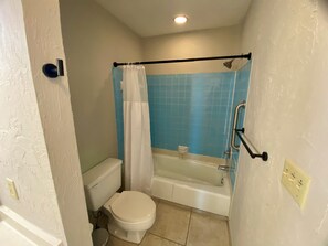 Une petite salle de bain comprenant des toilettes, une baignoire et un espace douche.