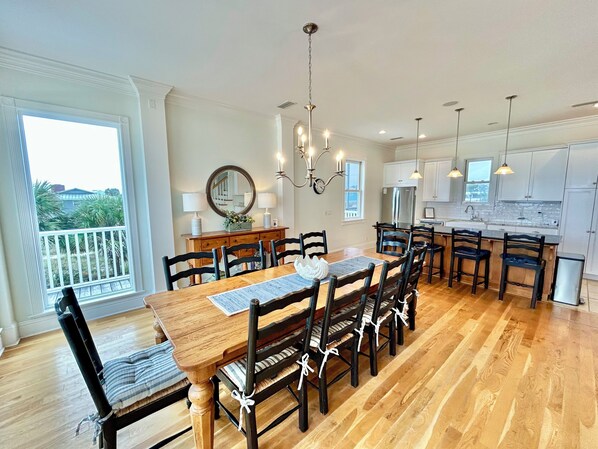Un comedor amplio con una mesa y sillas de madera, un candelabro y vistas al exterior.