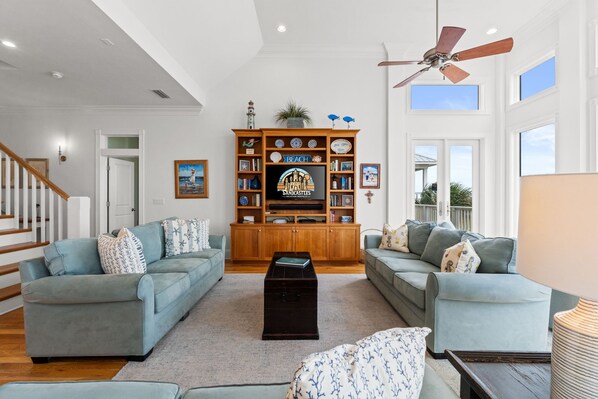 A spacious living room with two sofas, a coffee table, and a television on a wooden cabinet.